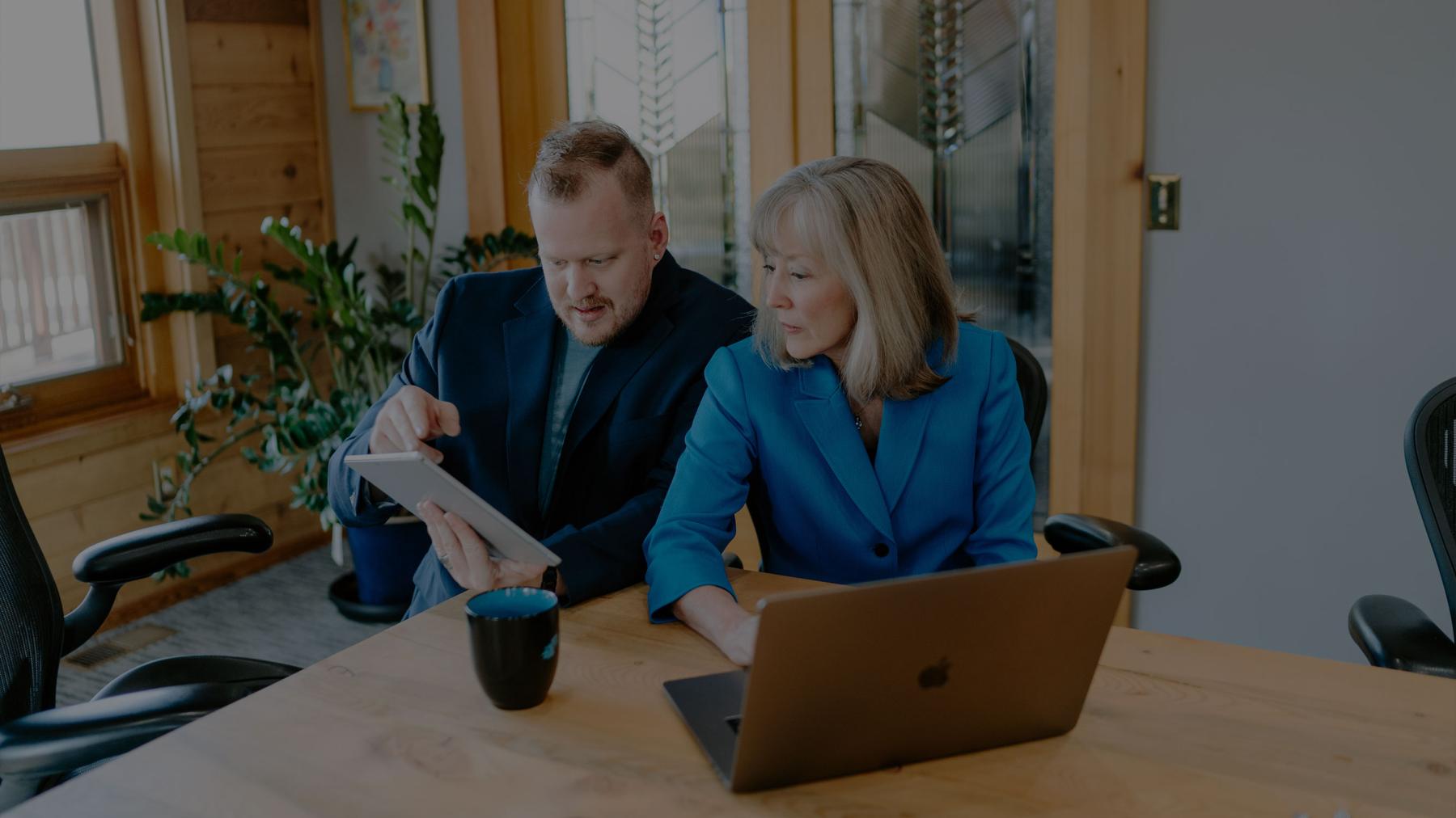 A man and woman talking and looking at computer tablet